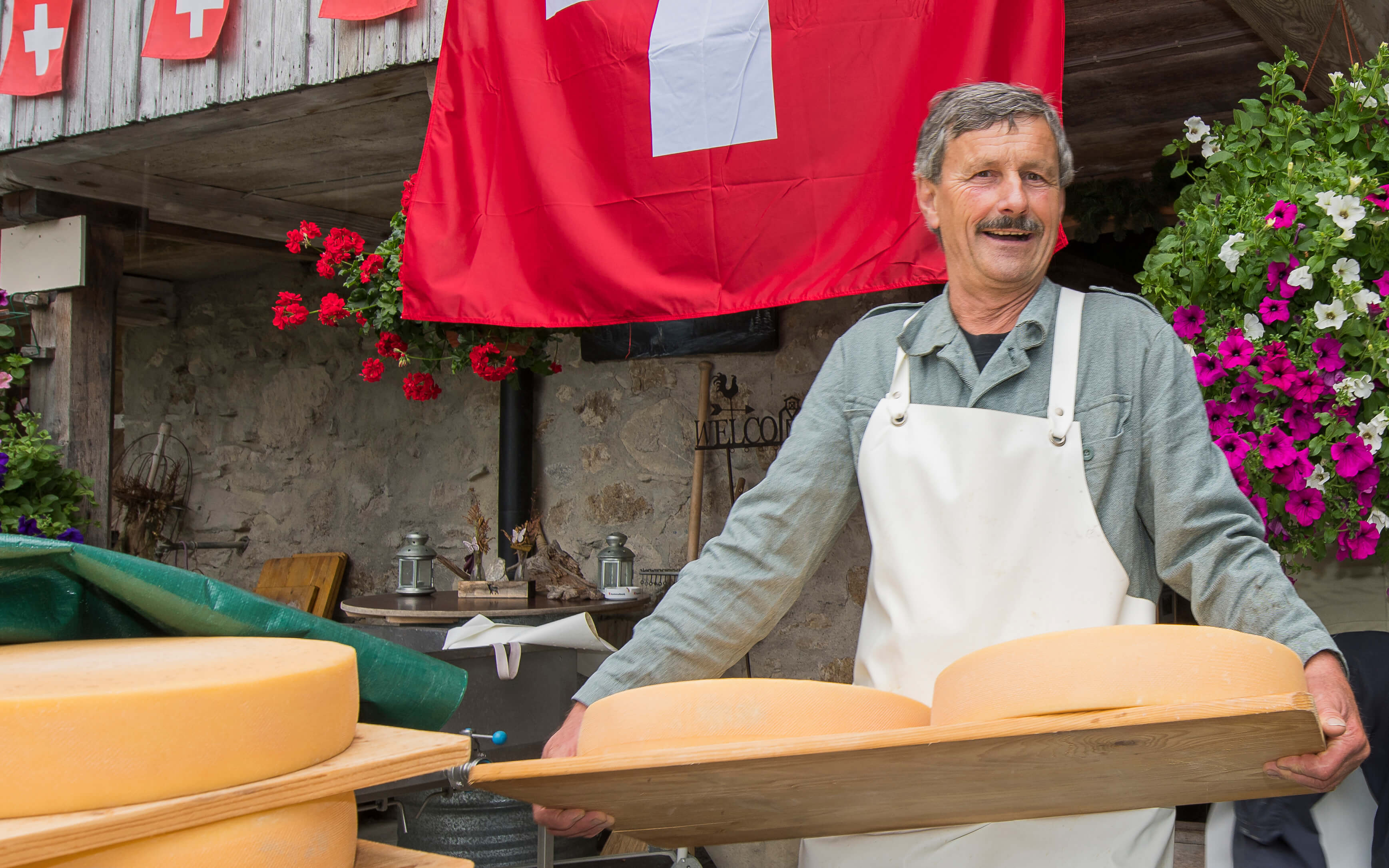 Foto Der Alpkäse wird zum Ausliefern auf Holzbrettern aus dem Keller getragen - zum Foto