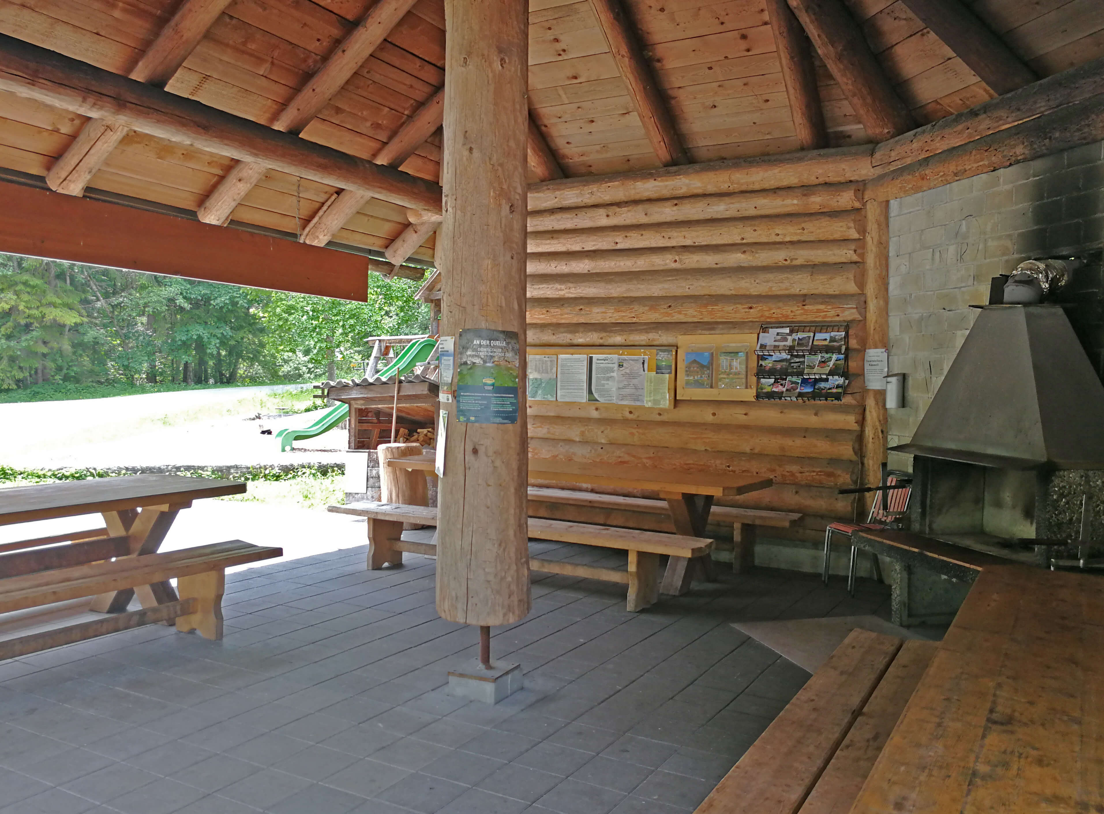 Gedeckte Rundholzhütte mit Feuerstelle, Tischen und Bänken