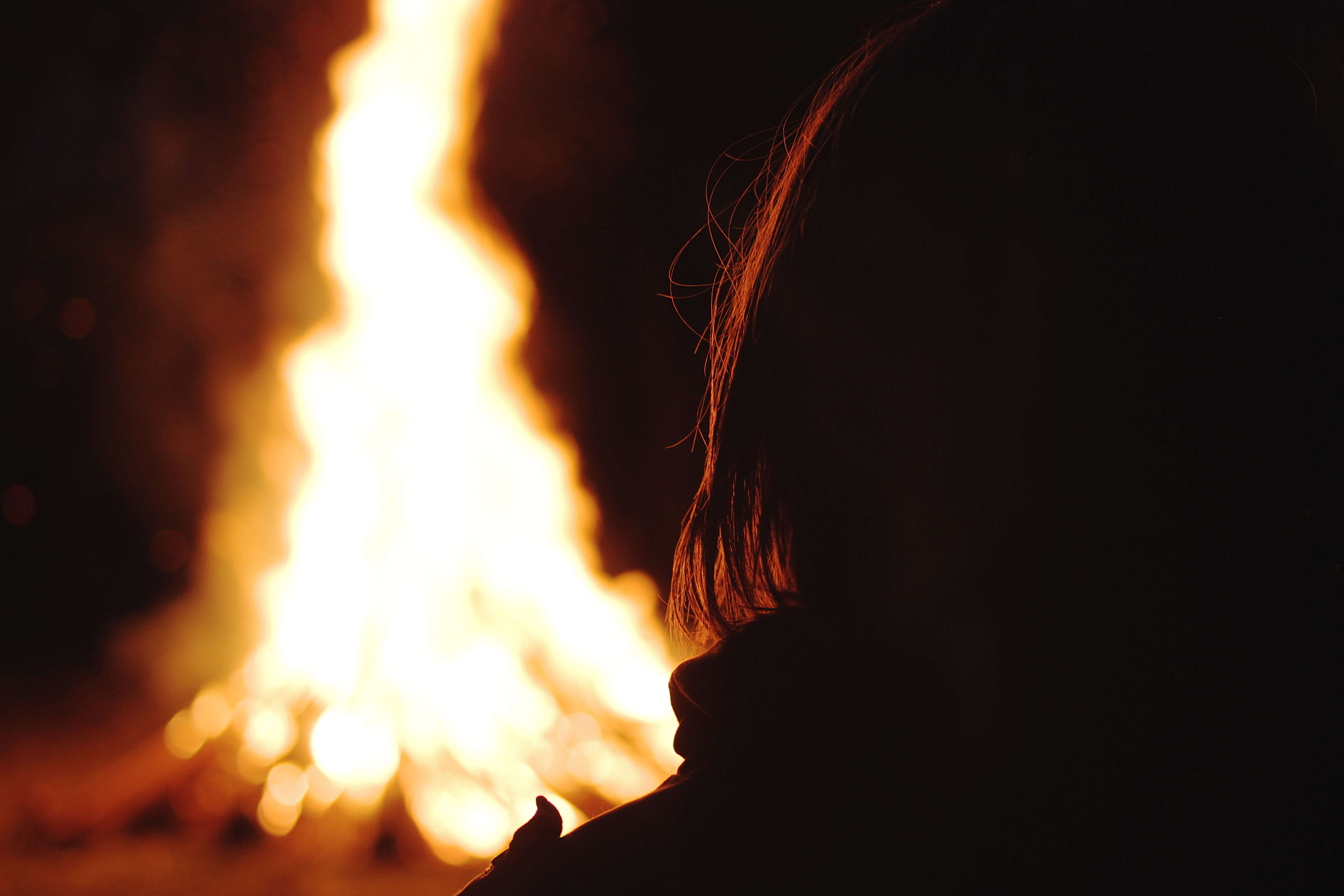 Foto Person sitzt am nächtlichen Lagerfeuer - zum Foto