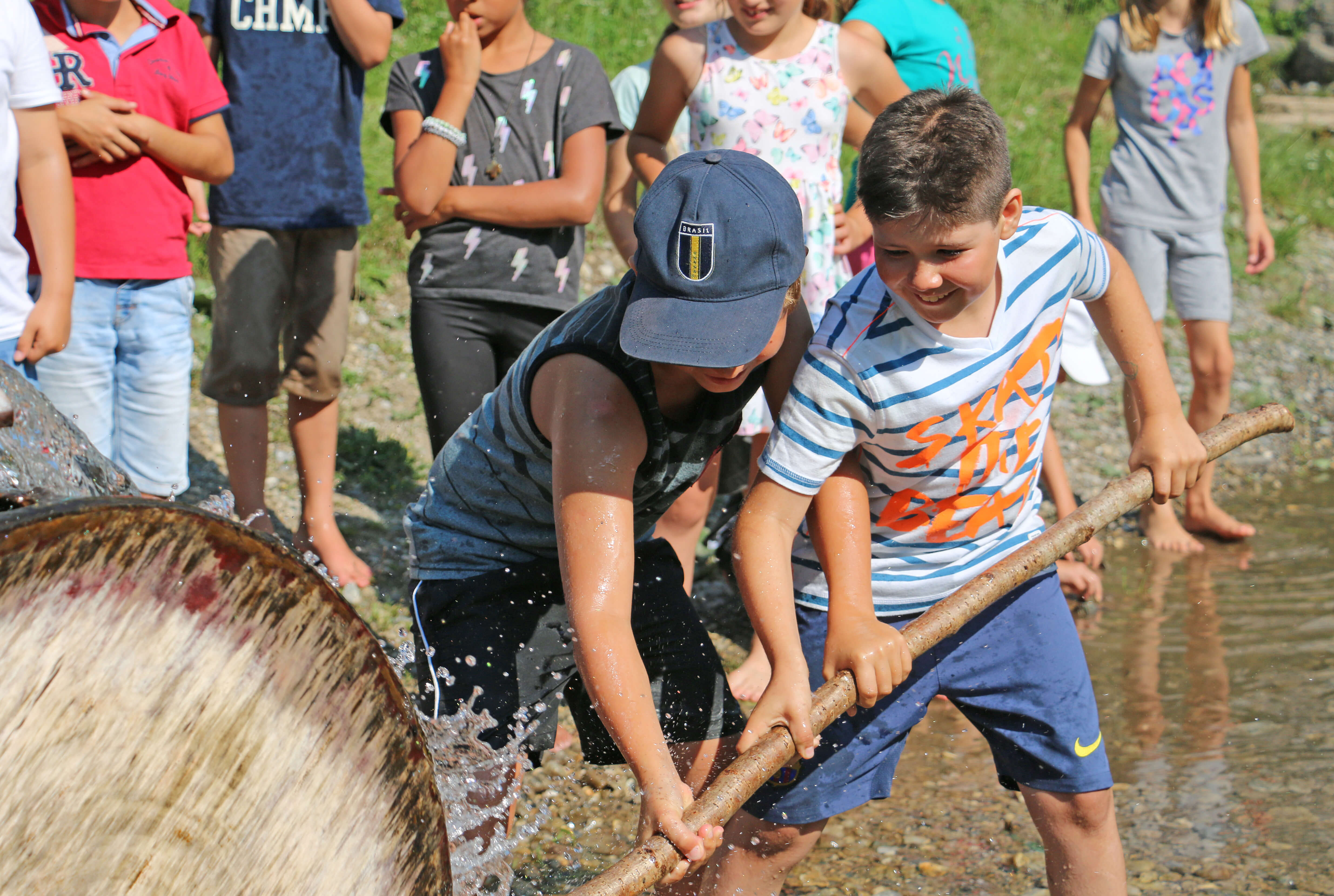 Foto Kinder versuchen mit einem Stecken ein Wasserrad zum Halten zu bringen - zum Foto