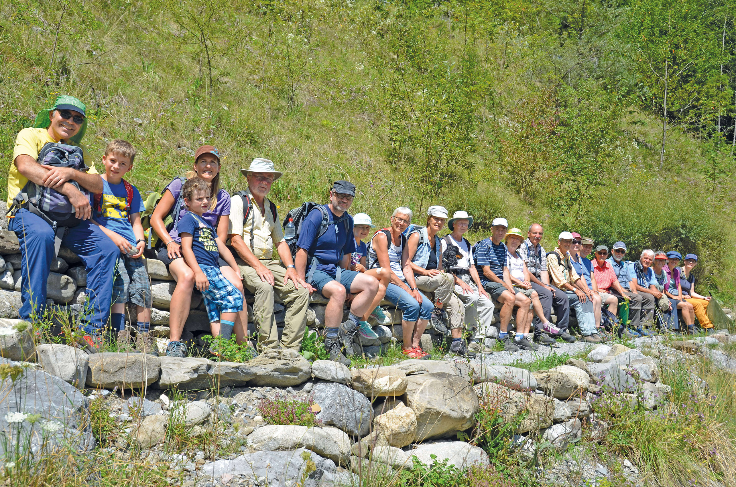 Foto Die Exkursionsteilnehmer sitzen auf einer Trockensteinmauer - zum Foto
