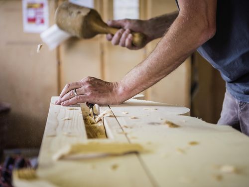 Nahaufnahme Zimmermann arbeitet mit Meissel und Hammer