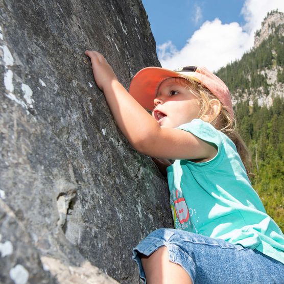 Foto Mädchen klettert an Steinwand hoch - zum Foto