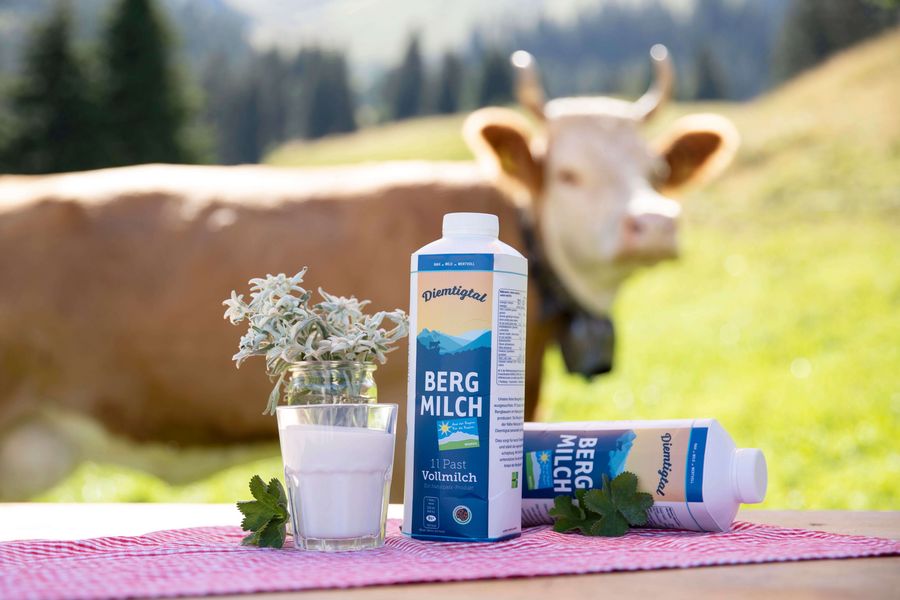 Tisch mit zwei Flaschen Diemtigtaler Bergmilch. Dahinter ist eine Simmentaler Kuh zu sehen.
