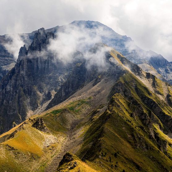 Mit Nebelschwaden verhangene Berge - zum Foto
