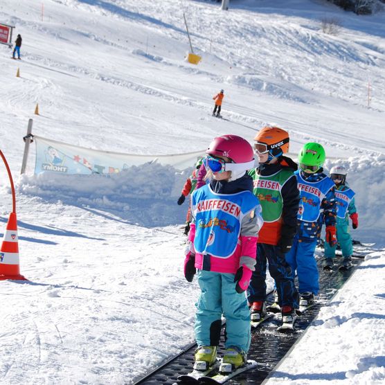 Photo Children stand on a magic carpet and ride up the slope - to the photo